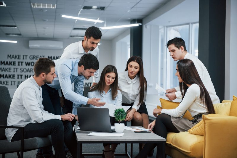 Colleagues gathered around a laptop reviewing a document together